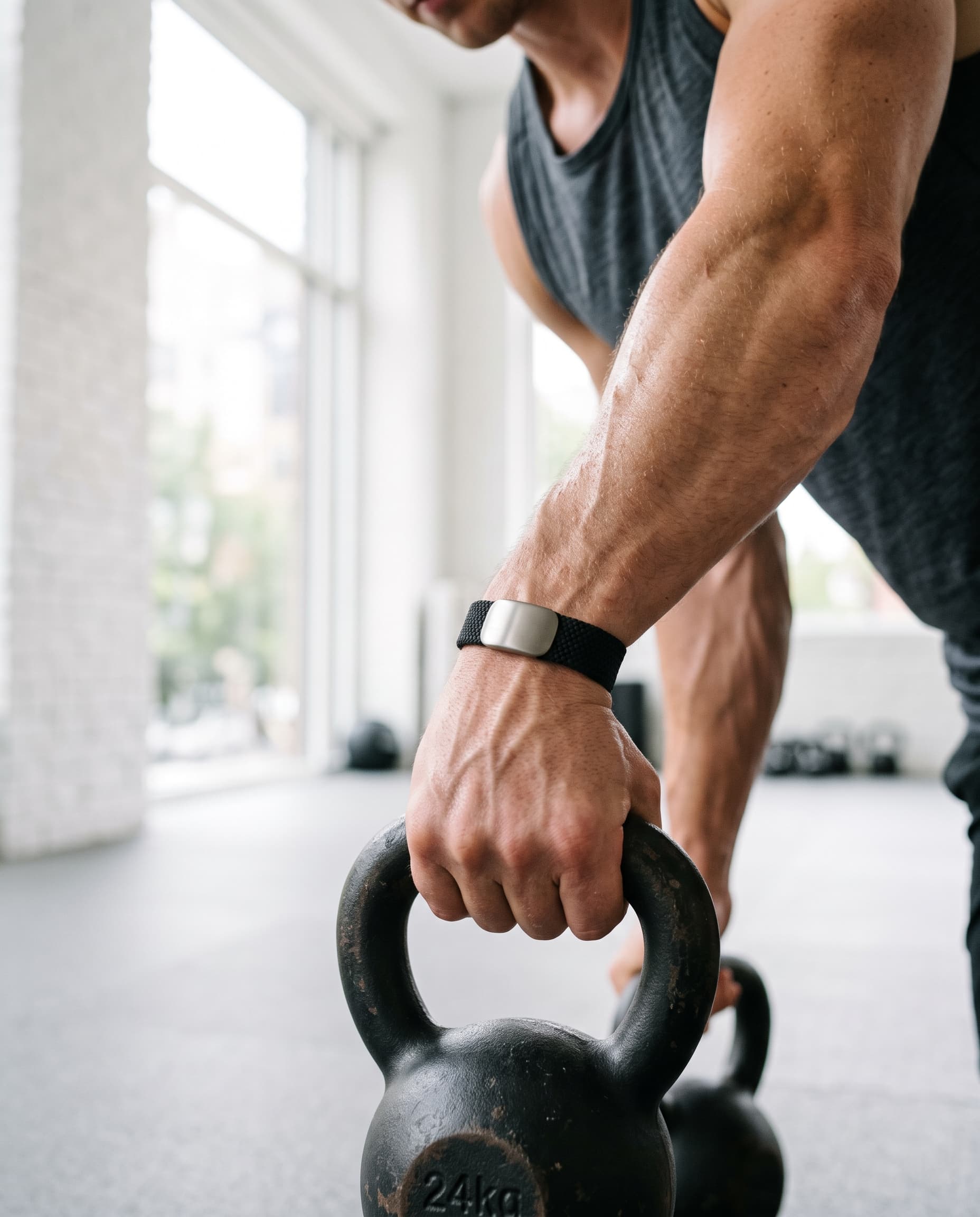 An athlete gripping a 24 kg kettlebell while wearing a black PACE Band